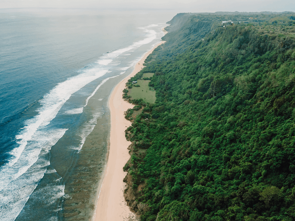Weißer Sandstrand von Nyang Nyang Beach unter hohen Kalksteinklippen in Bali